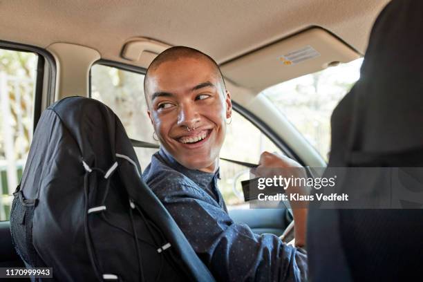 smiling male hipster fastening seat belt in car - auto spaß stock-fotos und bilder