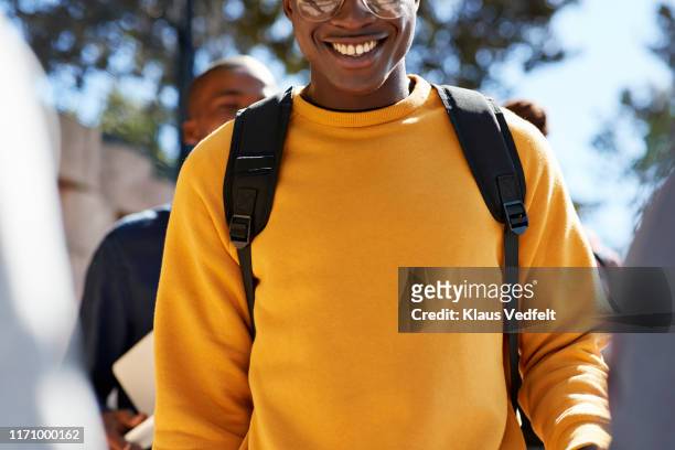 smiling young male student wearing yellow t-shirt - schulrucksack stock-fotos und bilder