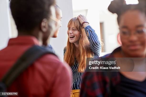 cheerful student with hand in hair amidst friends - adult student fotografías e imágenes de stock