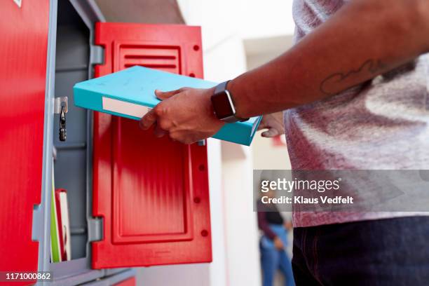 young male student removing file from locker - south africa map stockfoto's en -beelden