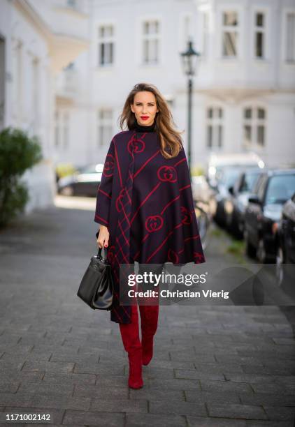 Alexandra Lapp is seen wearing a blue red Gucci cape, Hermès So Black Kelly bag, red suede Gianvito Rossi over the knee boots, black Marc Cain...