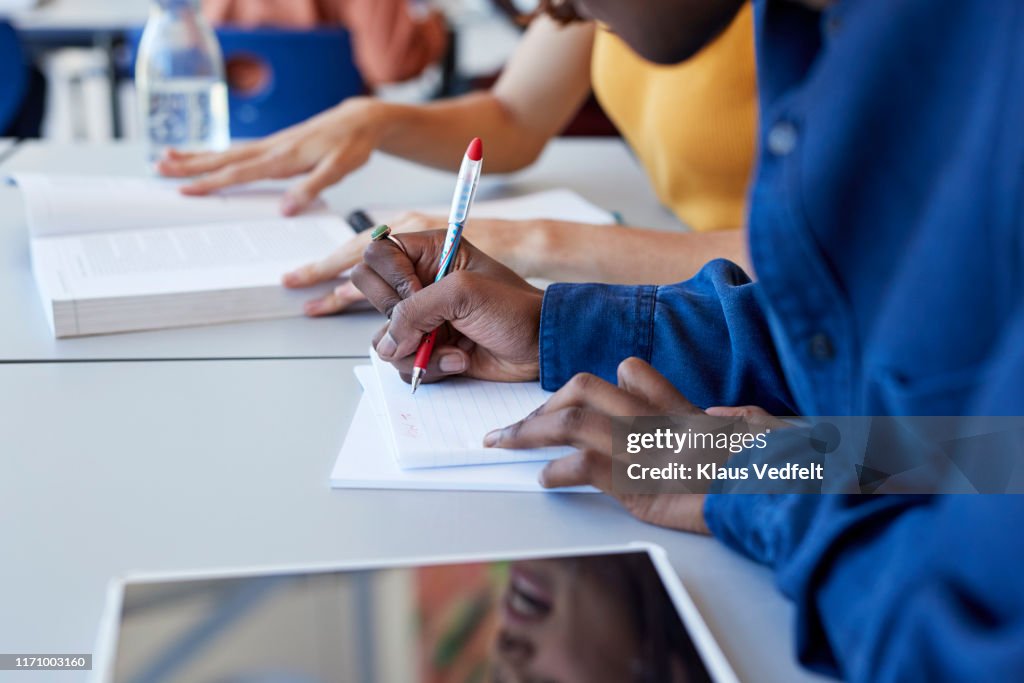 Man writing in book while sitting with friend