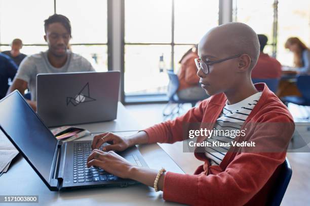 bald young woman using laptop at desk in classroom - shaved head profile stock pictures, royalty-free photos & images