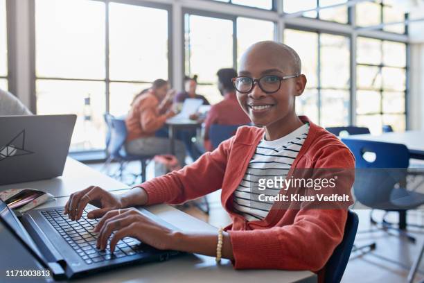 smiling bald young woman using laptop in classroom - stralende lach stockfoto's en -beelden