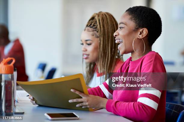 cheerful woman sitting by friend in classroom - women in suspenders fotografías e imágenes de stock