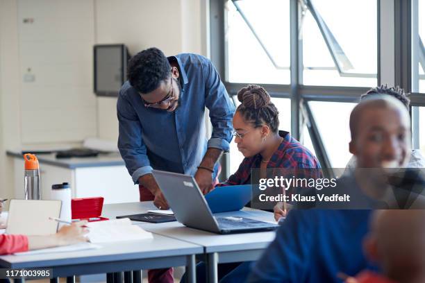 male teacher explaining female student at desk - assistant professor photos et images de collection