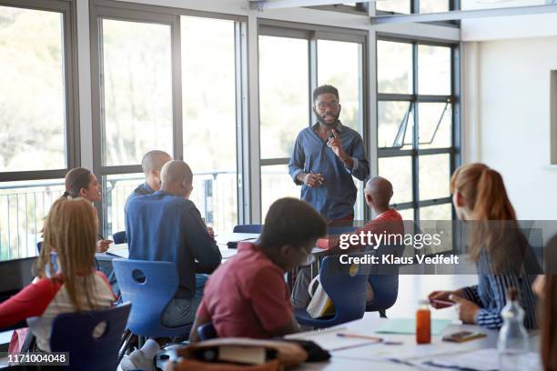 confident young male professor explaining students - inclusive classroom stockfoto's en -beelden