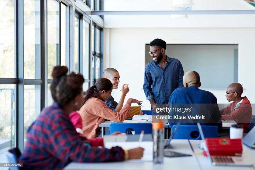 Smiling professor teaching students in classroom