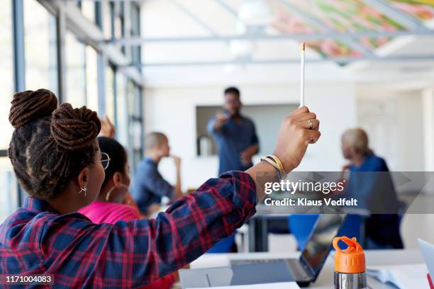 woman with hand raised holding pencil - school teacher blue stock-fotos und bilder