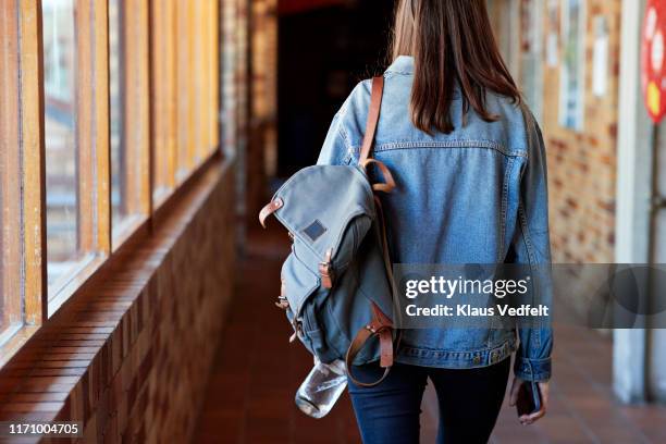 young woman with backpack walking in corridor - denim jacket fotografías e imágenes de stock