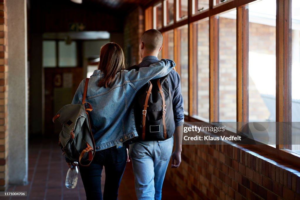 Young male and female friends walking in corridor