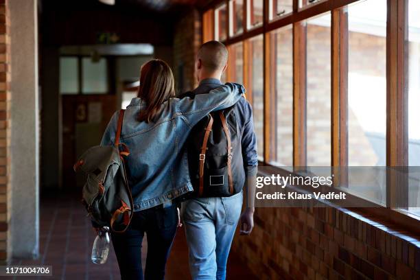 young male and female friends walking in corridor - couple school stockfoto's en -beelden