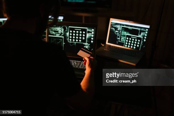 hacker usando computadoras portátiles y robando información de tarjetas de crédito - identity theft fotografías e imágenes de stock