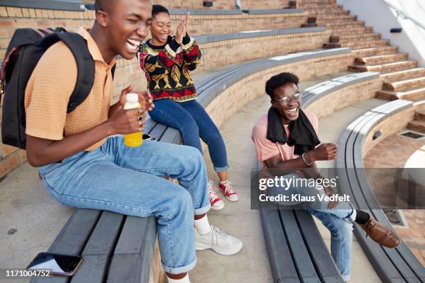 cheerful young friends enjoying on steps at campus - zwarte spijkerbroek stockfoto's en -beelden