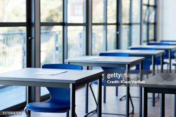 papers on desks by window in classroom - vazio - fotografias e filmes do acervo