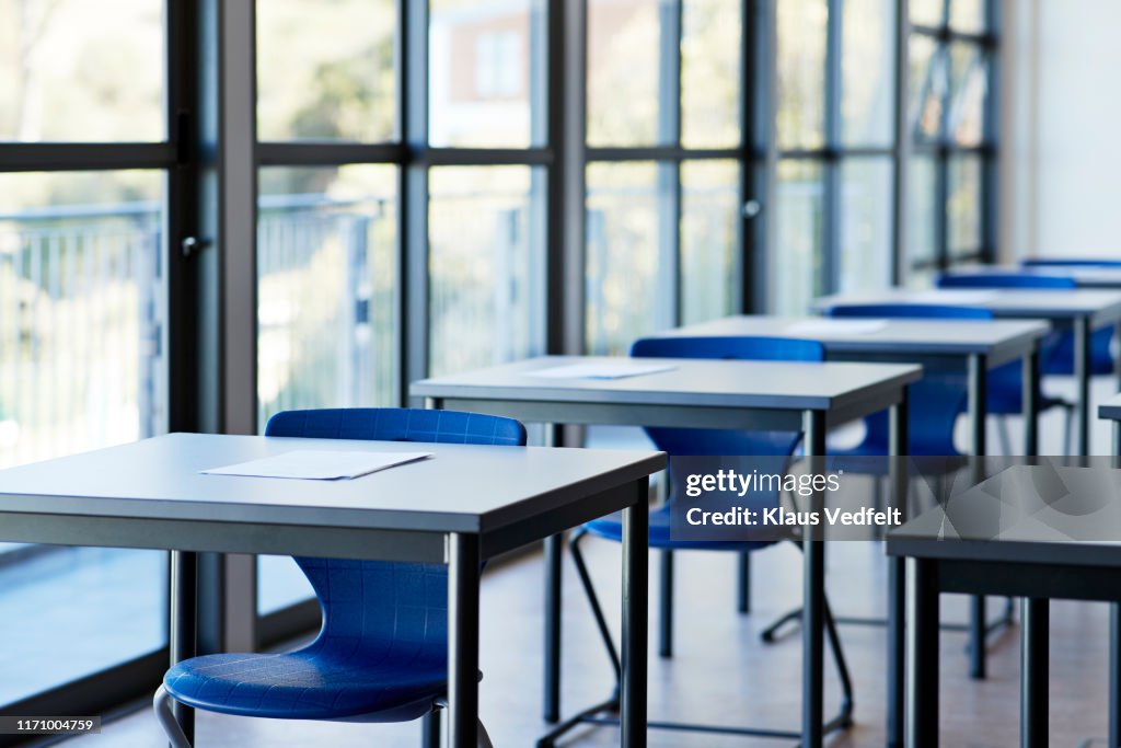 Papers on desks by window in classroom