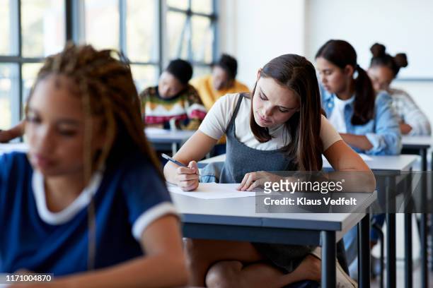 young multi-ethnic female students writing exam - tentamenzaal stockfoto's en -beelden