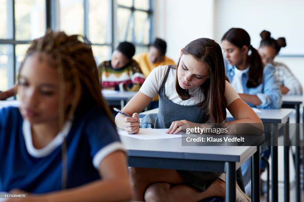 Young multi-ethnic female students writing exam