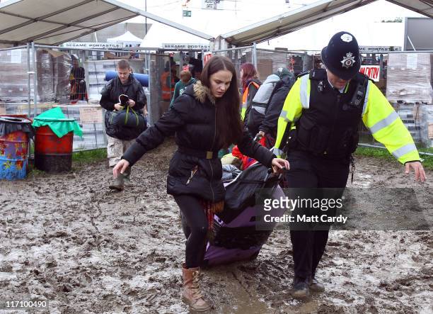 Police officer helps a festival goer with her camping gear as she arrives at the Glastonbury Festival site at Worthy Farm, Pilton on June 22, 2011 in...