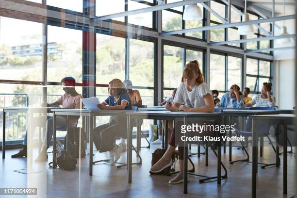 young female and male students writing exam - exam photos et images de collection