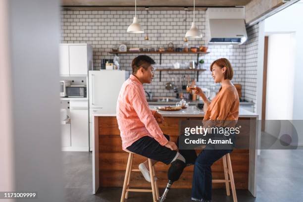 asian male amputee and wife relaxing in kitchen with tea - the japanese wife stock pictures, royalty-free photos & images