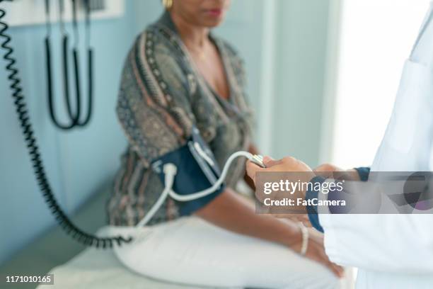 mature adult woman has blood pressure checked - medicaid stock pictures, royalty-free photos & images