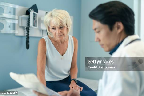 doctor shares test results with senior female patient - doctor with male patient reading notes stock pictures, royalty-free photos & images