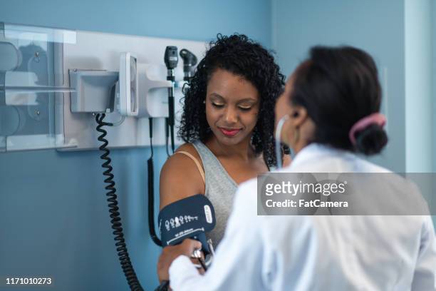 jonge vrouw in medisch overleg met een vrouwelijke arts - vrouwenkwesties stockfoto's en -beelden