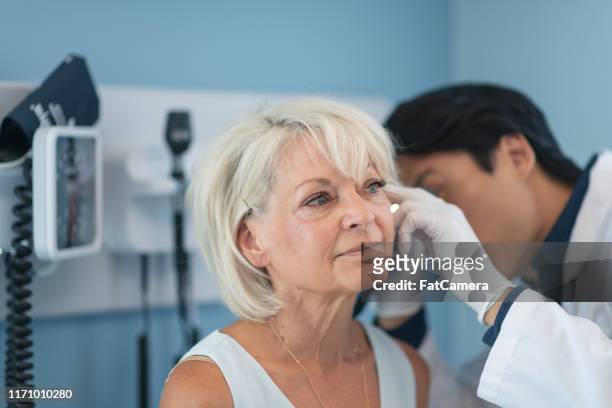 mature adult woman in medical consultation with male doctor - hearing aids stock pictures, royalty-free photos & images