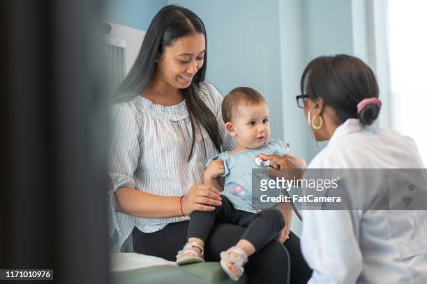 weibliche kinderärztin überprüft herz des babys mädchen in arzttermin - doctor and baby stock-fotos und bilder