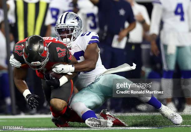 Jordan Leggett of the Tampa Bay Buccaneers is tackled by Justin March of the Dallas Cowboys in the first quarter during a NFL preseason game at AT&T...
