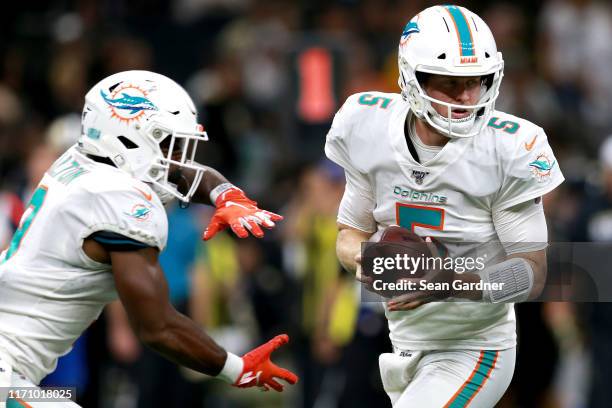 Jake Rudock of the Miami Dolphins hands the ball off to Mark Walton of the Miami Dolphins during a NFL preseason game at the Mercedes Benz Superdome...
