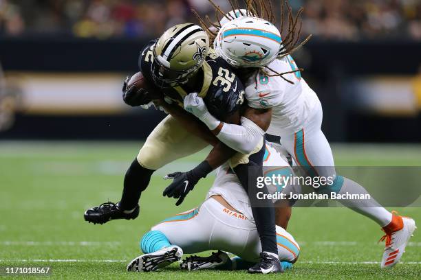 Jacquizz Rodgers of the New Orleans Saints is tackled by Terrance Smith and Torry McTyer of the Miami Dolphins during the first half of an NFL...