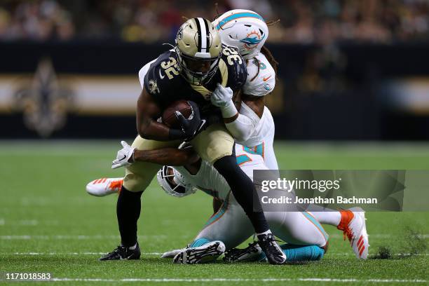 Jacquizz Rodgers of the New Orleans Saints is tackled by Terrance Smith and Torry McTyer of the Miami Dolphins during the first half of an NFL...