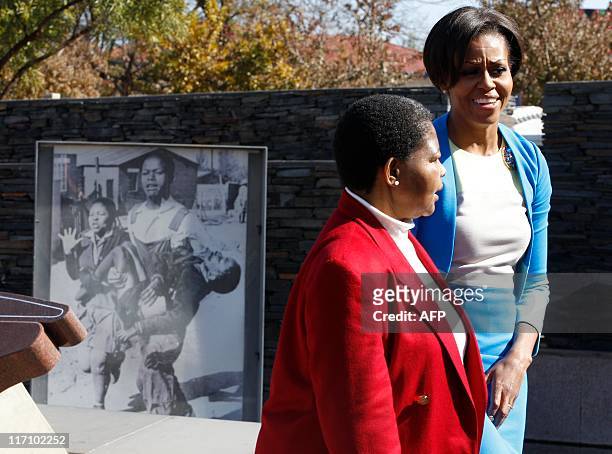 First lady Michelle Obama walks with Antoinette Sithole past a photo of her late brother Hector Pieterson was taken following his shooting, after...