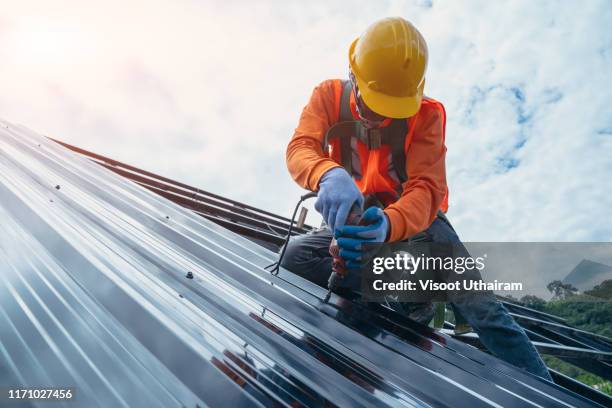 roofer worker in special protective work wear and gloves. - costruttore di tetti foto e immagini stock