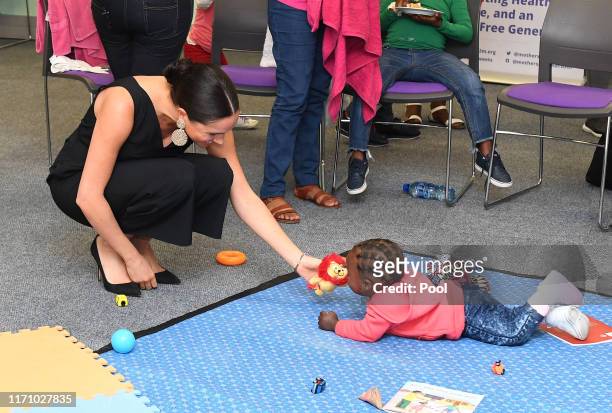Meghan, Duchess of Sussex plays with 15 month old Asivile as she visits mothers2mothers during her royal tour of South Africa with Prince Harry, Duke...
