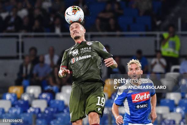 Cagliari's Italian defender Fabio Pisacane heads the ball as Napoli's Belgian forward Dries Mertens looks on during the Italian Serie A football...