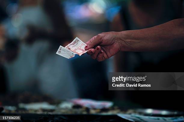 Customer pays for fish with Euro banknotes at a fish stand at the 'La Boqueria' fresh market on June 22, 2011 in Barcelona, Spain. Eurozone finance...