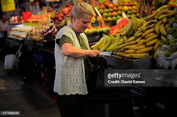 Customer checks his changes after buying vegetables with Euro banknotes at a fruit and vegetables stand at the 'La Boqueria' fresh market on June 22,...
