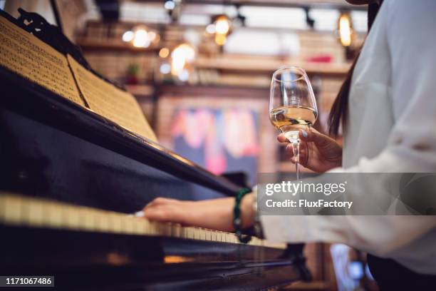 female piano player playing and drinking wine at a restaurant - piano stock pictures, royalty-free photos & images