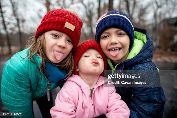 siblings outside catching snow on tongues during a winter snowfall - family with three children stock pictures, royalty-free photos & images