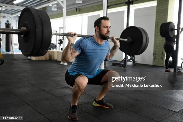 mid adult man weight lifting in gym - crouching stock pictures, royalty-free photos & images