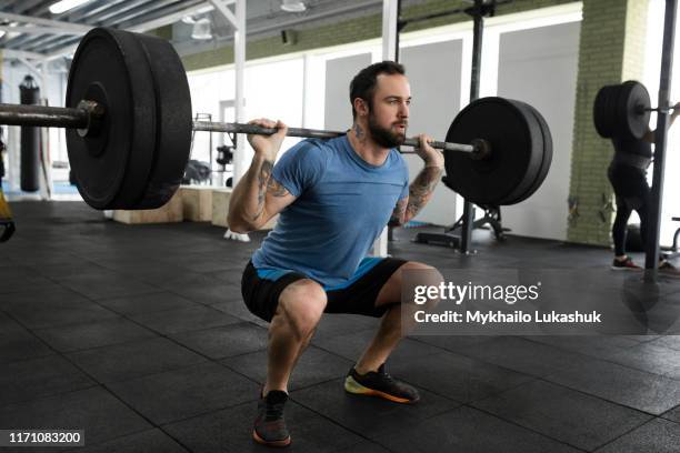 mid adult man weight lifting in gym - agachar se imagens e fotografias de stock