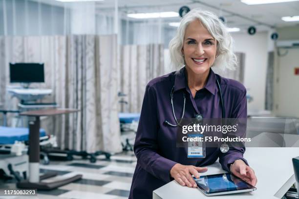 smiling doctor holding digital tablet in hospital - shirt stock pictures, royalty-free photos & images