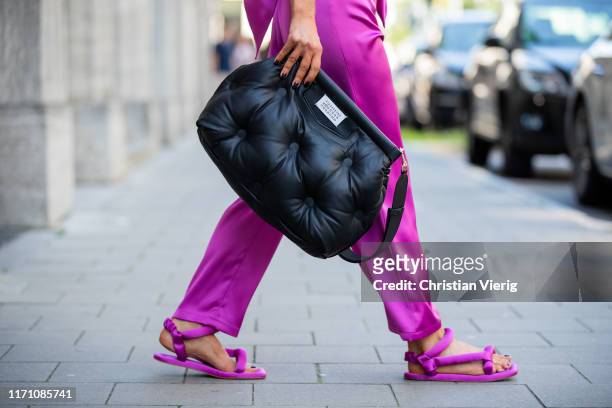 Gitta Banko is seen wearing a rosebud colored satin wide leg pants with rounded waistband, puffed shape flat Yolo sandals by Nanushka, a black...