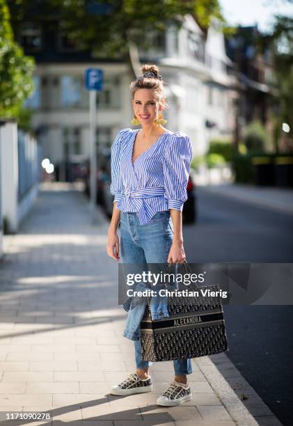 Alexandra Lapp is seen wearing a blue Dior Book Tote Dior Oblique, Goldsign blue jeans, a blue and white striped wrap blouse from Zara, Dior Oblique...