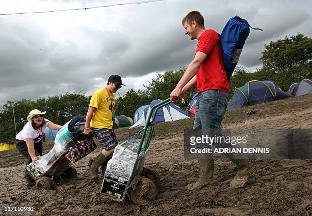 Revellers struggle to get their alcohol along the muddy paths as they arrive for the annual Glastonbury festival near Glastonbury, Somerset on June...