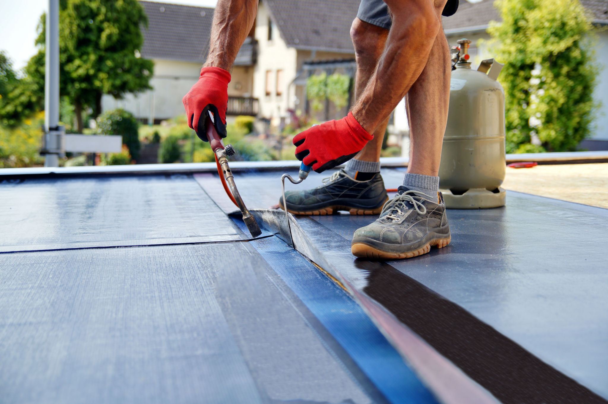 Flat roof installation with propane blowtorch during construction works with roofing felt. Heating and melting bitumen roofing felt. Flat roof installation with propane blowtorch during construction works with roofing felt. Heating and melting bitumen roofing felt.