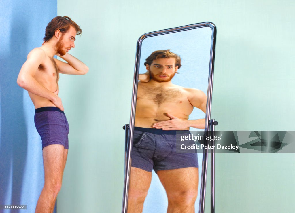 Man seeing an illusion of a fatter self in mirror